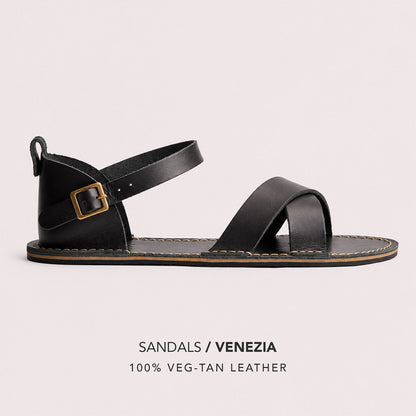 Nero | Flat leather sandals with ankle straps and debossed PLG three tree logo in soles, shown on a light gray background with text below reading 'SANDALS / VENEZIA' and '100% VEG-TAN LEATHER'.