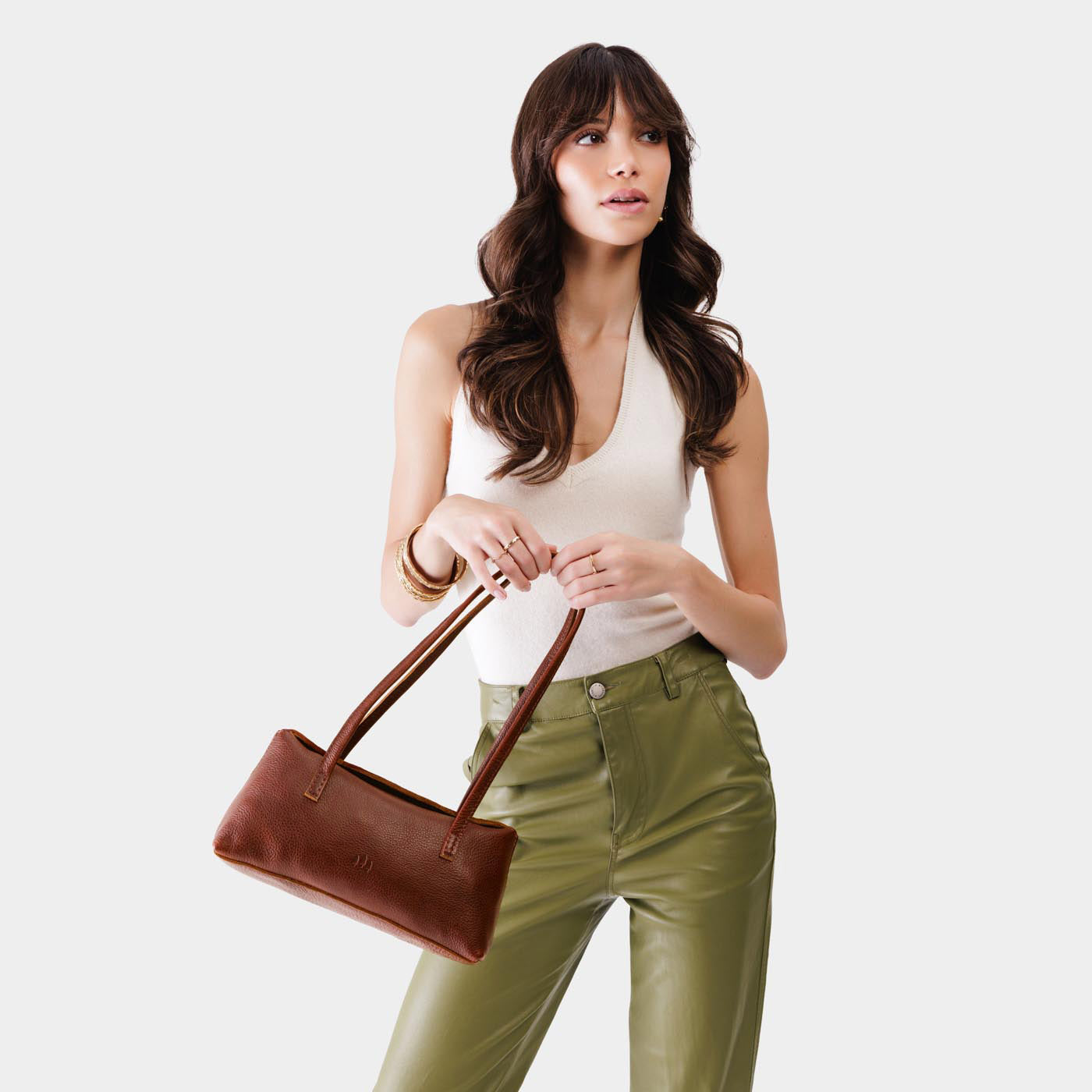 Nutmeg | Woman wearing a light brown leather bowler bag against a white background