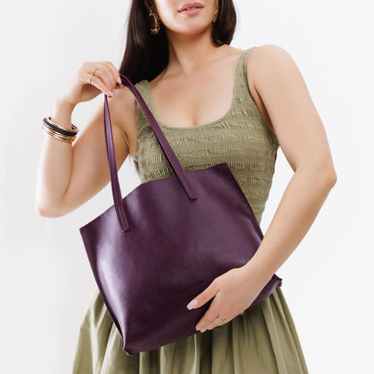 Plum*Medium | Model holding leather tote bag with interior snap key loop
