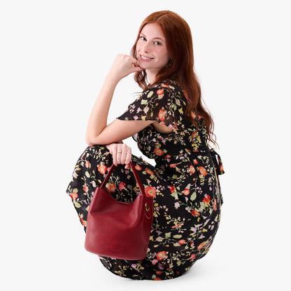Chili Red*Large | Model holding symmetrical bucket bag with handle, latch closure, and removable crossbody strap