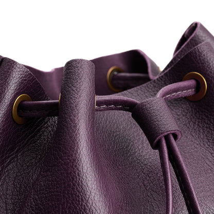 Plum | Close-up of a leather drawstring backpack with grommets.