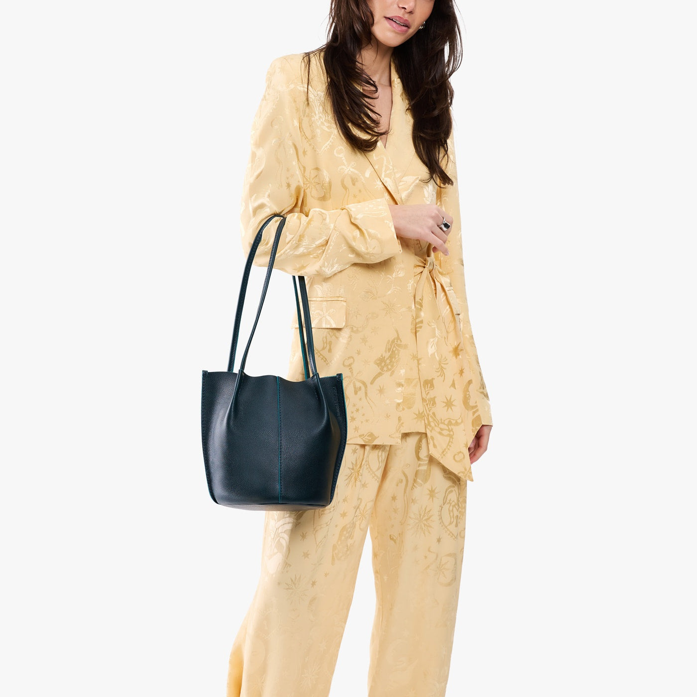 Boreal*Small | Model wearing matching light yellow shirt and trousers carrying petite bucket shaped tote bag with matching leather handles