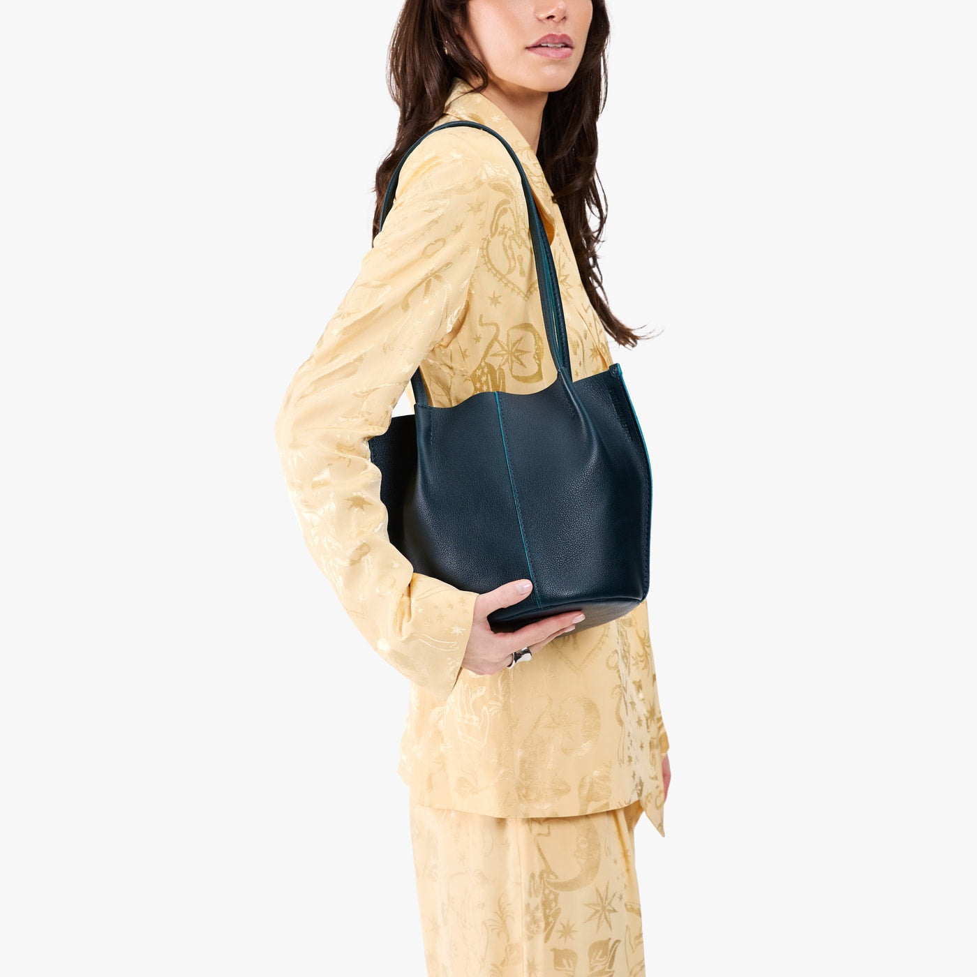 Boreal*Small | Model wearing matching light yellow shirt and trousers carrying petite bucket shaped tote bag with matching leather handles