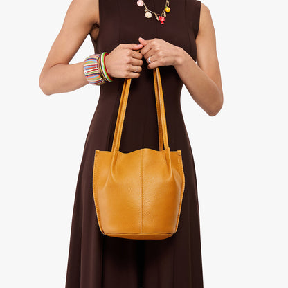 Sunshine*Small | Model wearing dark brown dress holding petite bucket shaped tote bag with matching leather handles