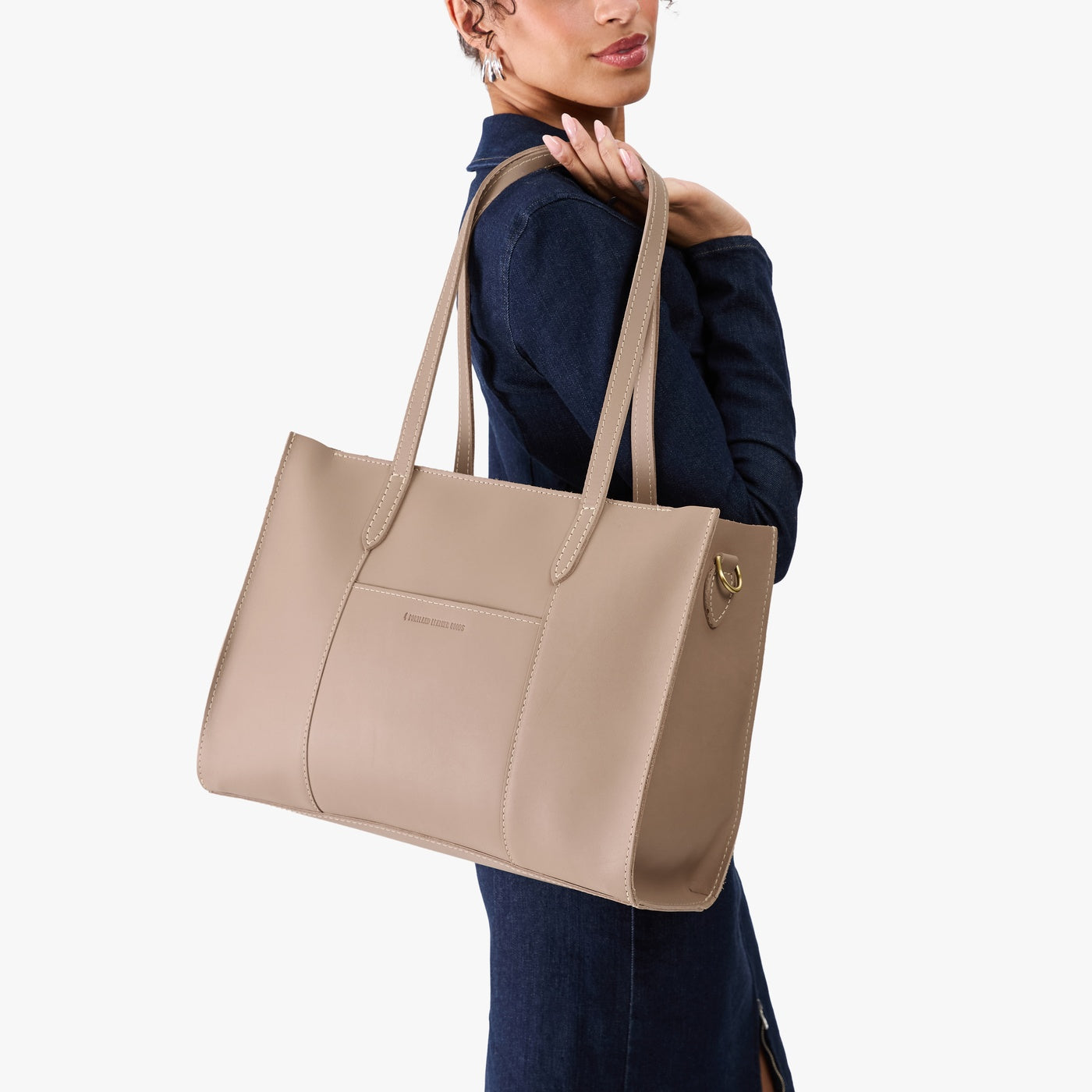 Stone*Oversized East/West | Model holding structured wide tote bag with overlapping panels and crossbody strap