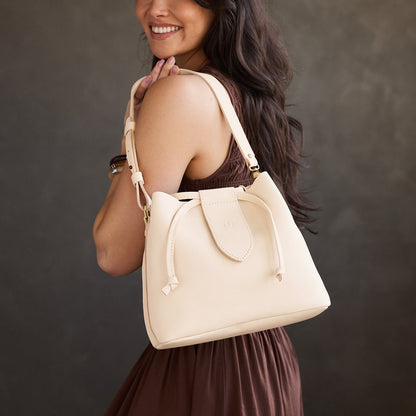 Pebbled Bone*Large | Model holding symmetrical leather bag with leather drawstring closure and adjustable shoulder strap