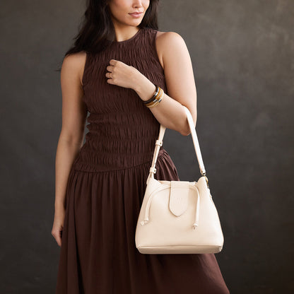Pebbled Bone*Large | Model holding symmetrical leather bag with leather drawstring closure and adjustable shoulder strap