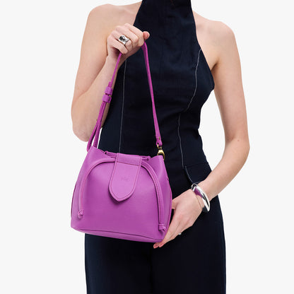 Cattleya*Small | Model holding symmetrical leather bag with leather drawstring closure and adjustable shoulder strap