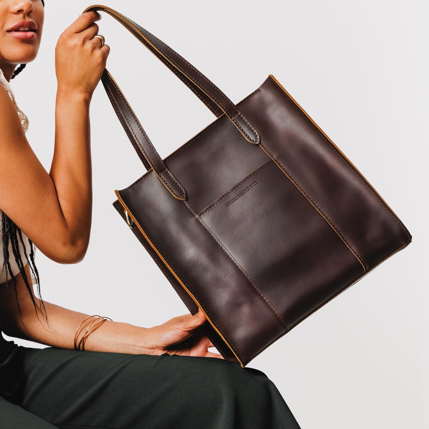 Grizzly*North/South | Model holding structured large tote bag with overlapping panels and crossbody strap