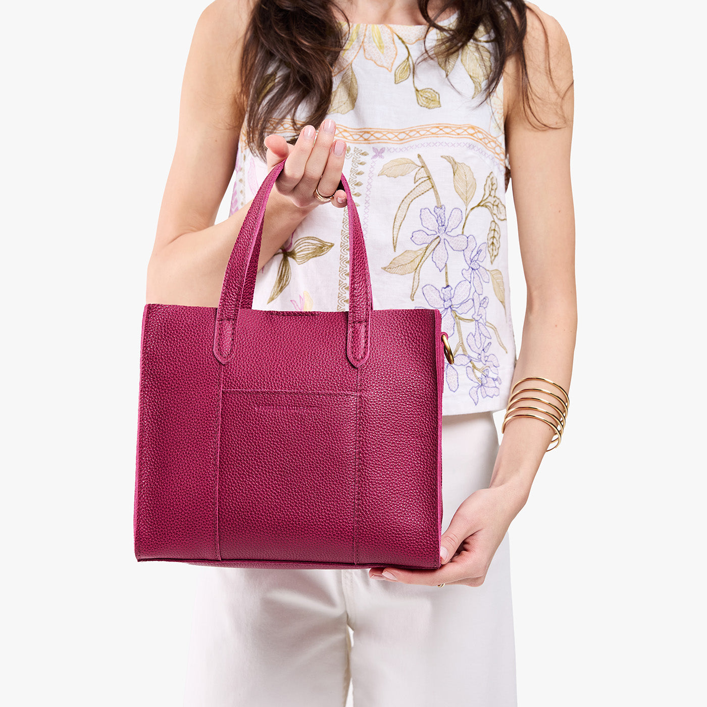 Cosmo | Model holding structured mid-size tote bag with overlapping panels and crossbody strap