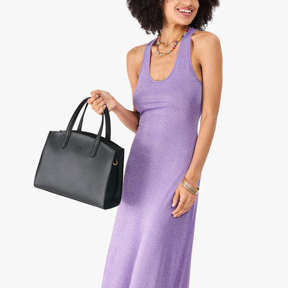 Black*Medium | Model carrying leather tote bag with handles, adjustable crossbody strap, and two back pockets