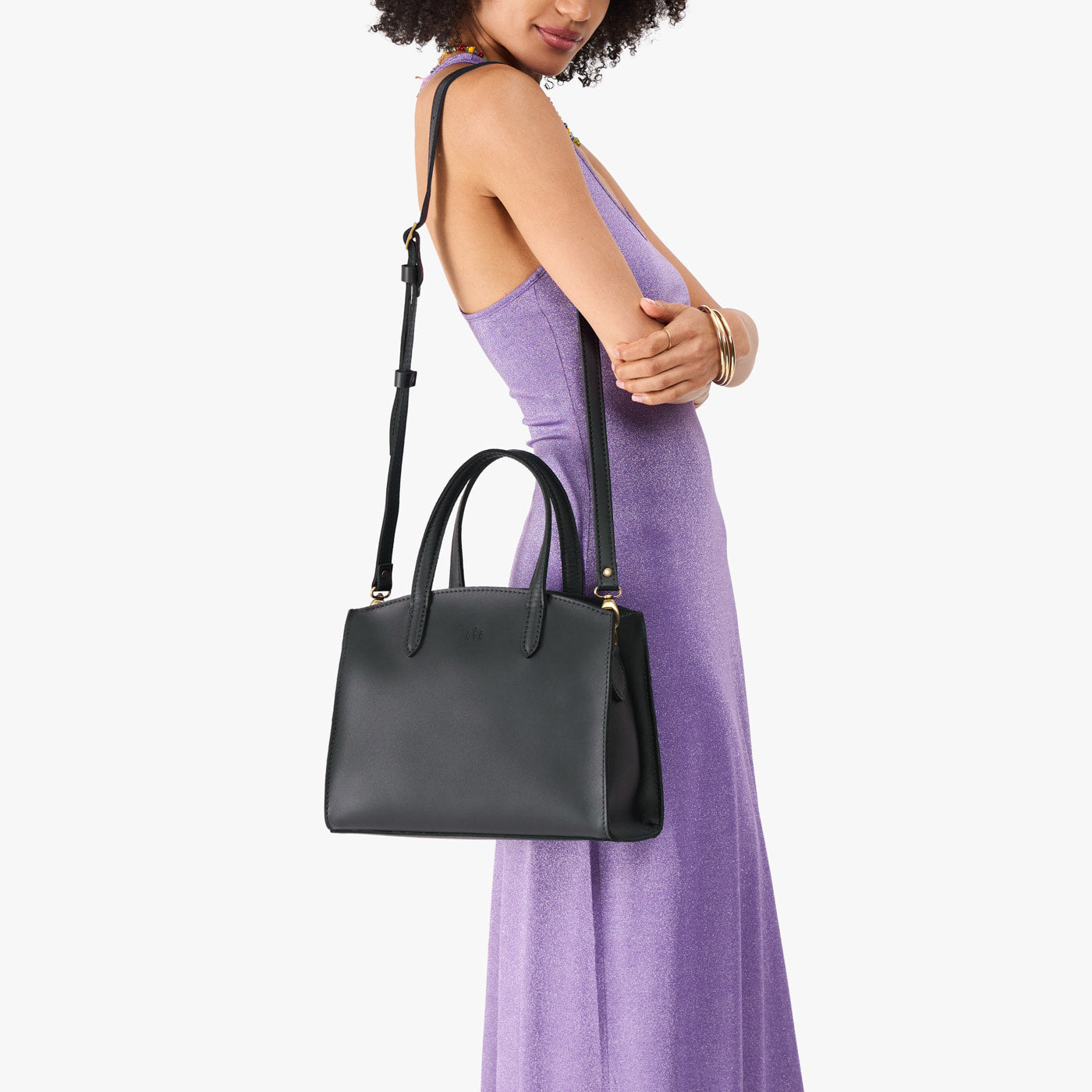 Black*Medium | Model carrying leather tote bag with handles, adjustable crossbody strap, and two back pockets