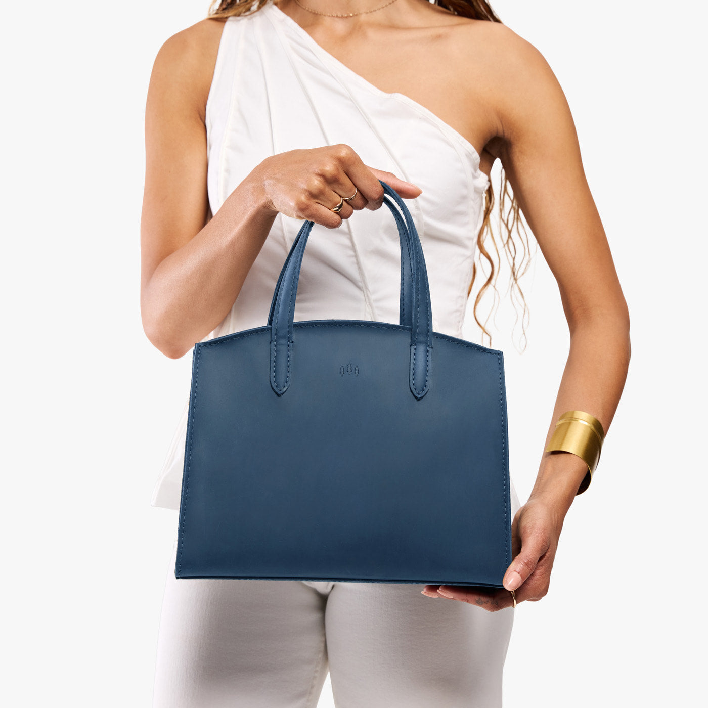 Deep Water*Medium | Model holding leather tote bag with handles, adjustable crossbody strap, and two back pockets