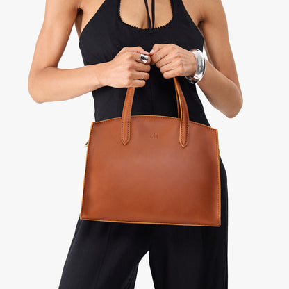 Honey*Medium | Model carrying leather tote bag with handles, adjustable crossbody strap, and two back pockets