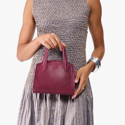 Orchid*Mini | Model holding small leather tote bag with handles, adjustable crossbody strap, and one back pocket