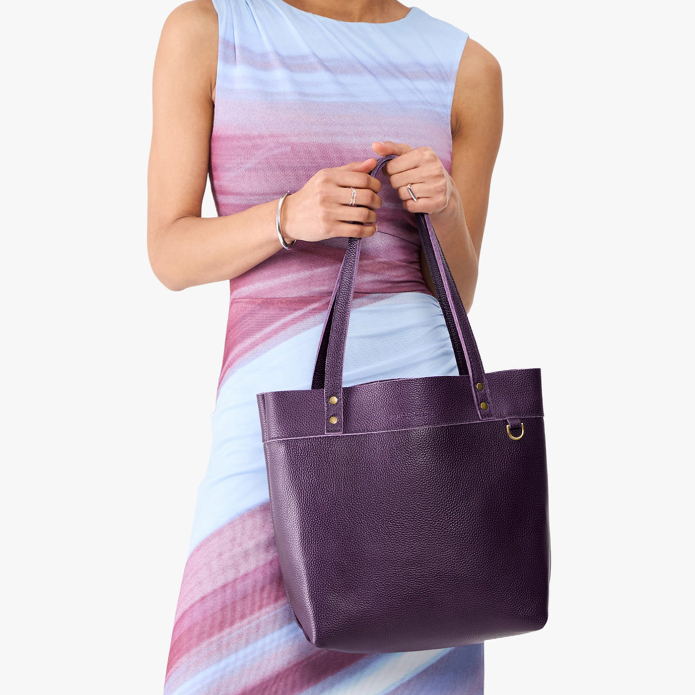 Empire | Model holding leather tote bag with riveted straps and exterior key loop