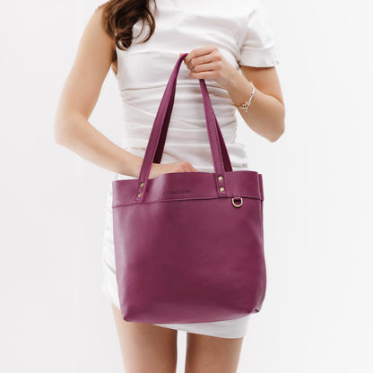 Iris*Medium*Classic | Model holding leather tote bag with riveted straps and exterior key loop