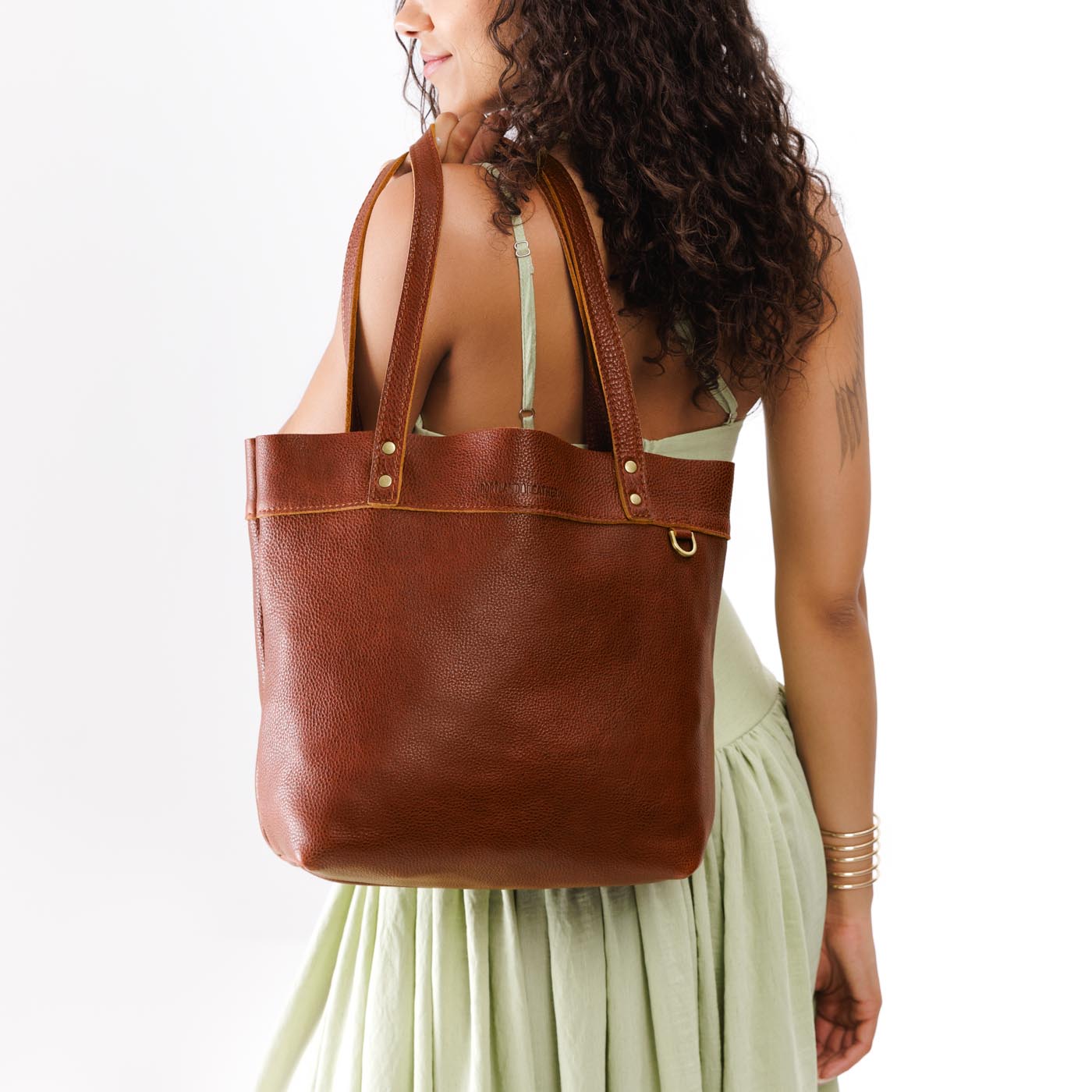 Nutmeg*Medium*Classic | Model wearing leather tote bag with riveted straps and exterior key loop