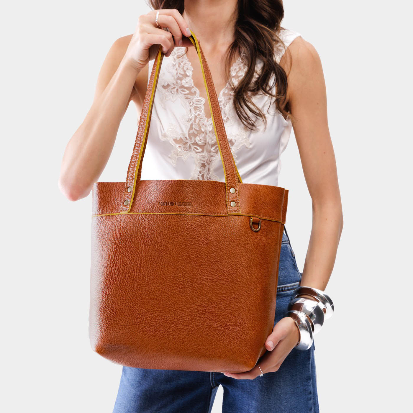 Sienna*Medium*Classic | Model holding a leather tote bag with riveted straps and exterior key loop