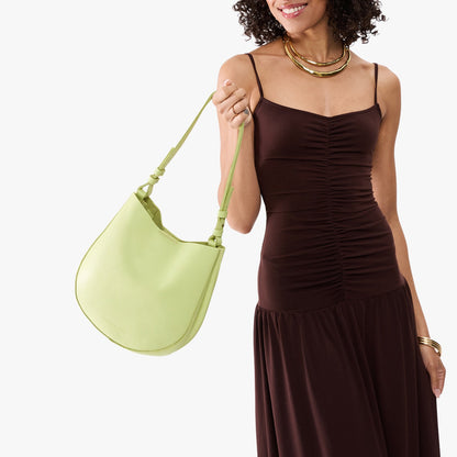 Shadow Lime*Medium | Model carrying round leather purse with adjustable shoulder strap