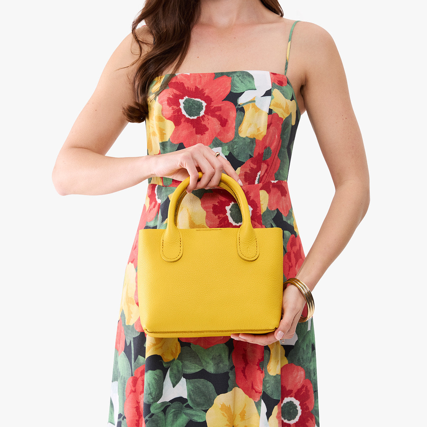 Canary*Small | Model holding a petite tote purse with structured leather handles and crossbody strap