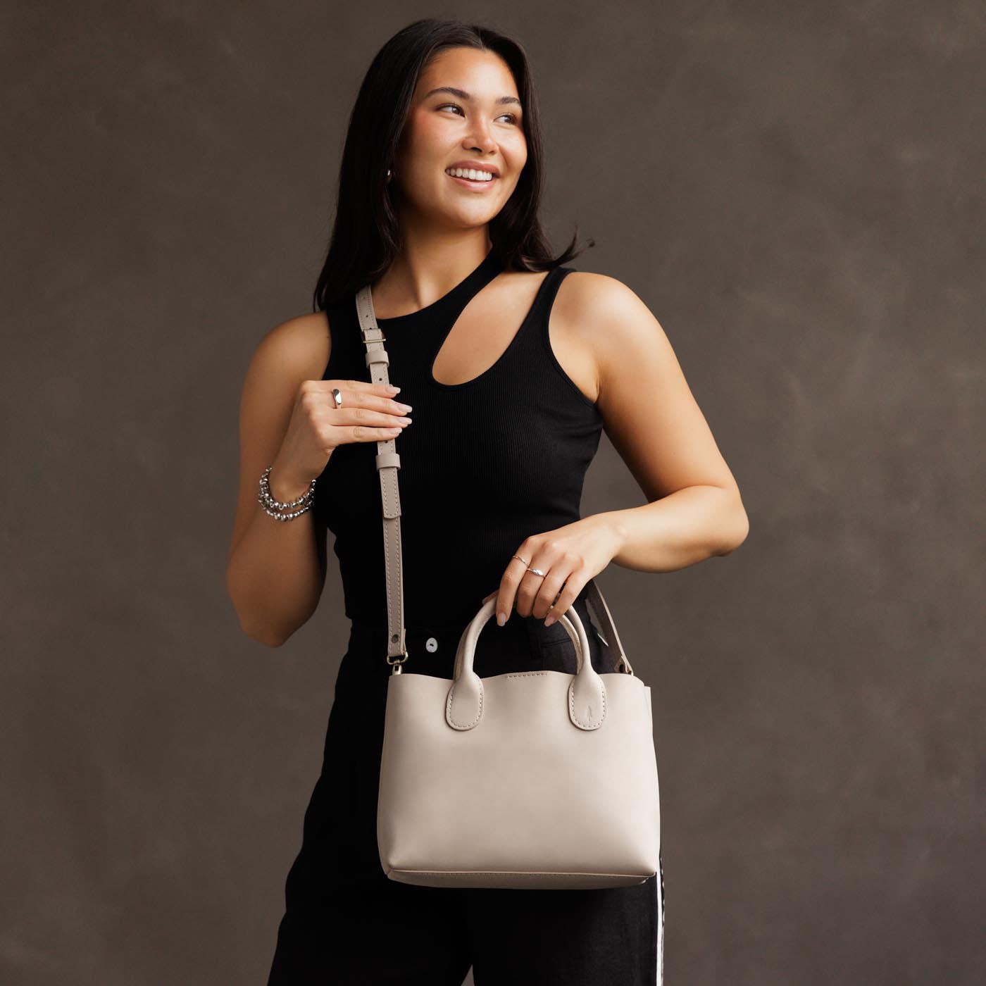 Dragon Bone*Large | Model holding mid-size tote purse with structured leather handles and crossbody strap