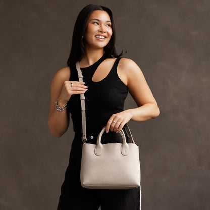 Dragon Bone*Large | Model holding mid-size tote purse with structured leather handles and crossbody strap