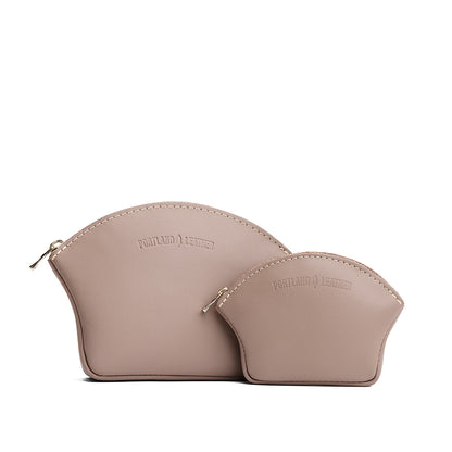 Stone | Comparison shot of small and large seashell shaped leather makeup bags with curved top zipper and flat bottom