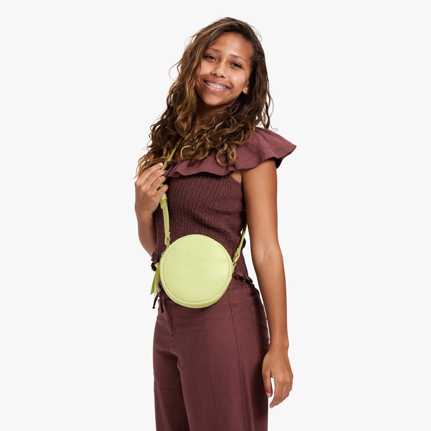 Shadow Lime | Model wearing a circle shaped crossbody bag with top zipper and gold accents
